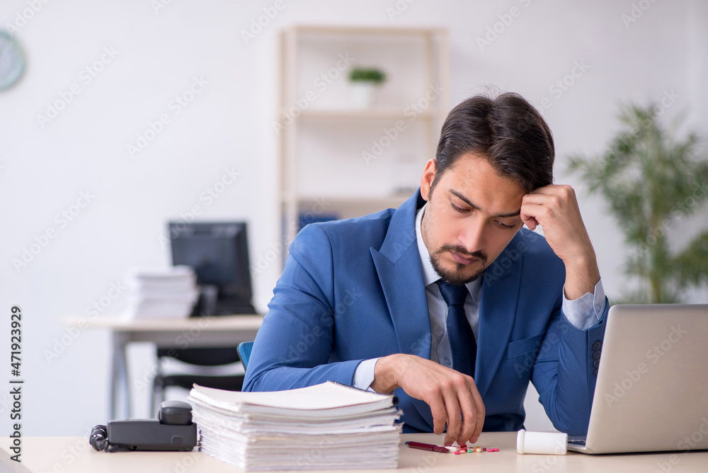 Young male employee suffering at workplace