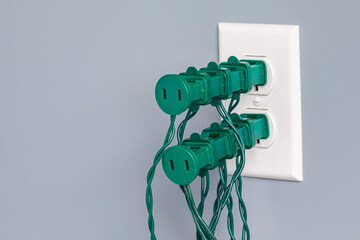 Electrical outlet overloaded with Christmas string lights. Holiday decoration safety, hazards and fire prevention concept.