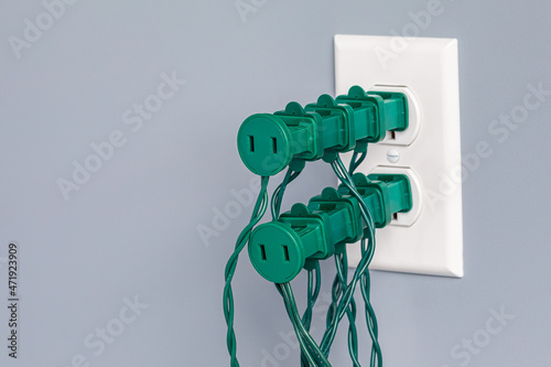 Electrical outlet overloaded with Christmas string lights. Holiday decoration safety, hazards and fire prevention concept.