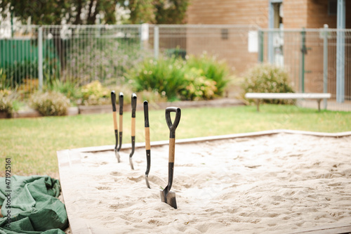 Fototapeta Row of children's shovels lined up in Preschool sandbox