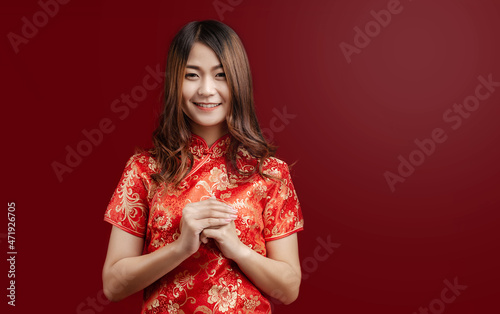 Beauty Asian woman in red chinese dress and smiling to you in chinese new year, on red background