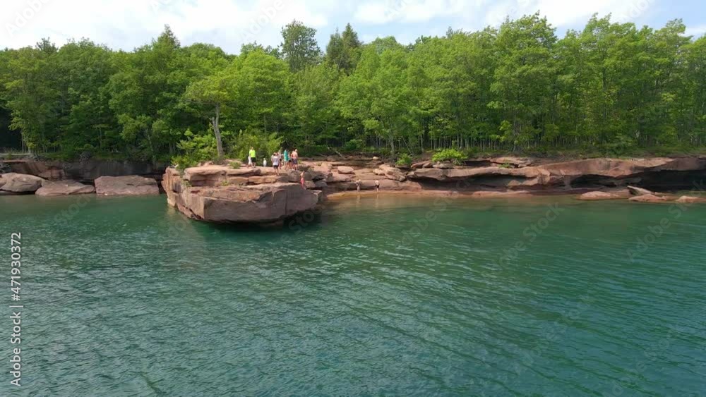 People cliff jumping from a rock into Lake Superior on a summer day