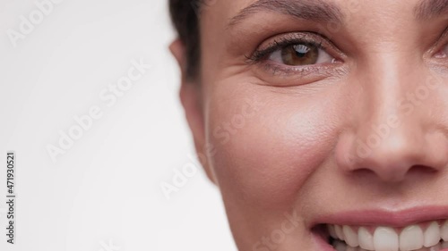 Close up view half face of beautiful female touching her face and look at the camera. Concept for fresh moisturized elasticity skin. Natural healthy face. hydrated skin care treatment.