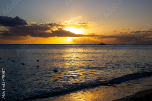 SUNSET ON THE BEACH WITH ORANGE LIGHT AND BLUE SKY WITH SOME CLOUDS