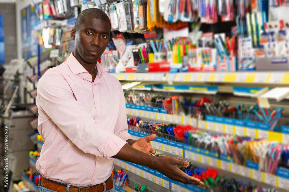 young male customer choosing new pen in stationery store