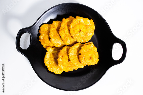 fried patacones on black plate with white background photo