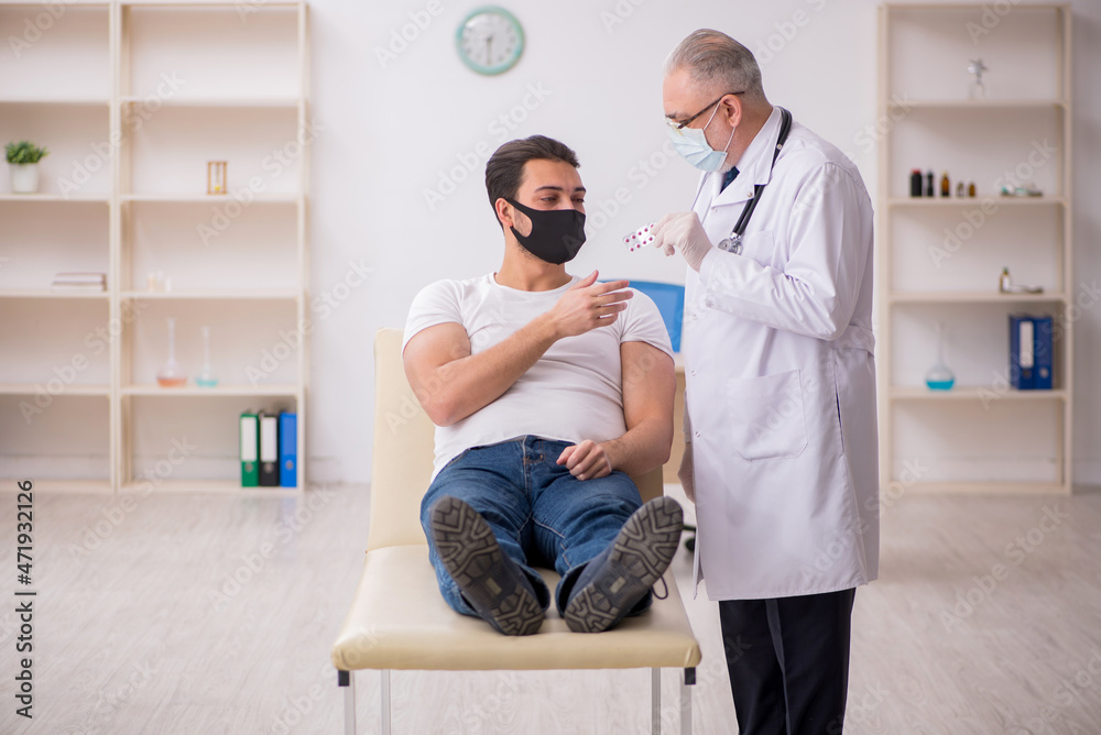 Fototapeta premium Young male patient visiting old doctor in vaccination concept