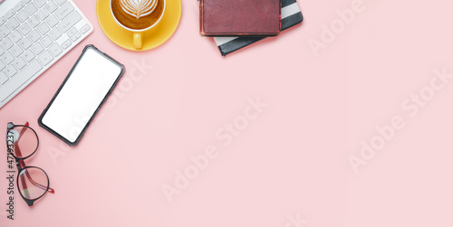 Office desk with computer, Blank screen smart phone, eyeglass, notebook, Cup of coffee on pink background, Top view with copy space, Mock up....
