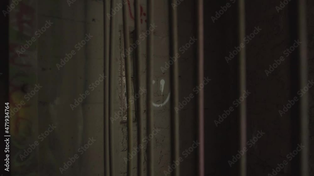 Pull back from within cage with smiley face painted on a wall, behind rusty bars, inside an abandoned building Pull back from within cage with smiley face painted on a wall, behind rusty bars, inside an abandoned building