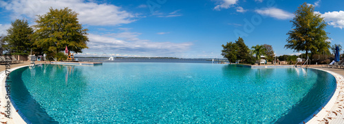 panoramic view of an infinity swimming pool in a resort with blue water and palm tree perfect for vacation © tamas