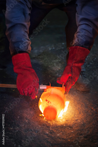 Checking diameter of a still red hot flaming crank shaft with a vernier photo