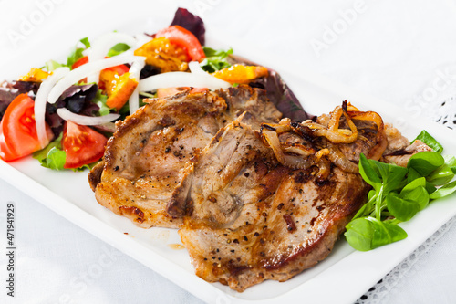 Cooked fried pork meat chops with salad of fried orange and vegetables