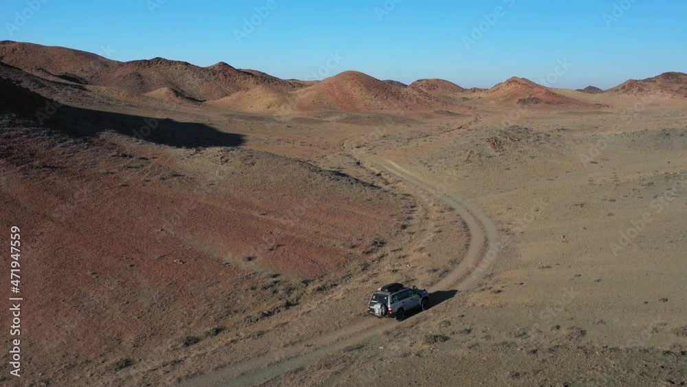 Cinematic drone shot of a lone car traveling in the Charyn Canyon, Kazakhstan Cinematic drone shot of a lone car traveling in the Charyn Canyon, Kazakhstan