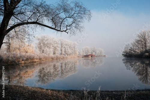 House by the lake. The transition of nature from autumn to winter. Foggy and sunny morning on the lake.