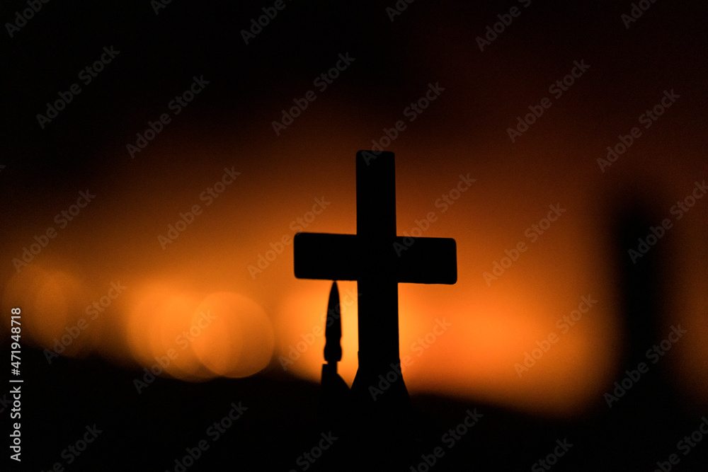 Silhouette of a cross in a cemetary during a wildfire