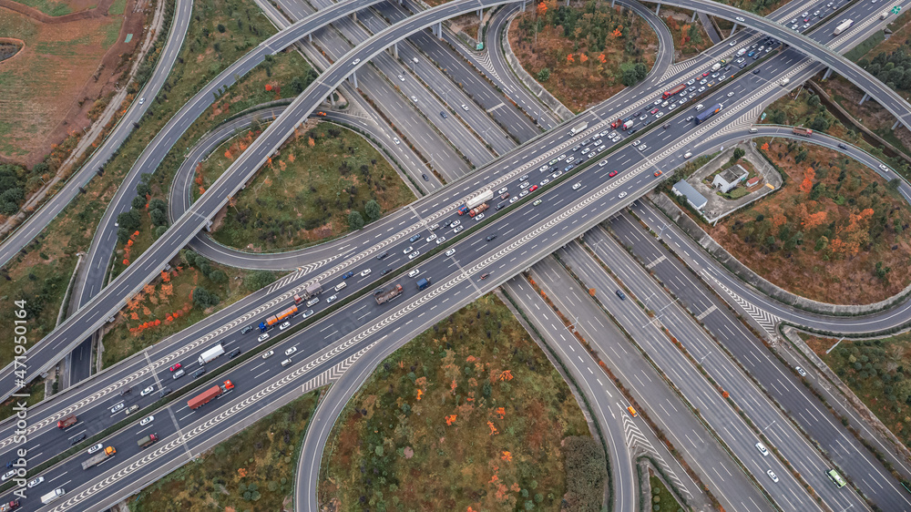 Top down aerial view from drone on modern traffic junction of multiple lane highway road in metropolis city. Heavy traffic on motorways. Elevated curved roads, clover shape bridge with no speed limit. Top down aerial view from drone on modern traffic junction of multiple lane highway road in metropolis city. Heavy traffic on motorways. Elevated curved roads, clover shape bridge with no speed limit.