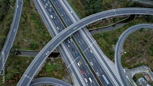 Top down aerial view from drone on modern traffic junction of multiple lane highway road in metropolis city. Heavy traffic on motorways. Elevated curved roads, clover shape bridge with no speed limit.