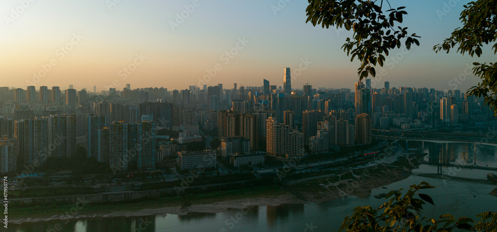 Obraz premium At sunset, in Chongqing, China, on the bank of the Jialing River, densely packed with high-rise buildings and bridges over the river, the afterglow of the setting sun falls on these buildings.