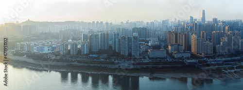 The city is in Chongqing  China. The river is called the Jialing River. At sunset  the city has warm sunlight afterglow