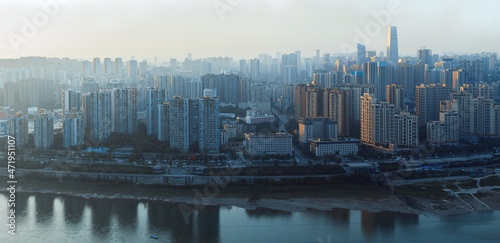 The city is in Chongqing  China. The river is called the Jialing River. At sunset  the city has warm sunlight afterglow