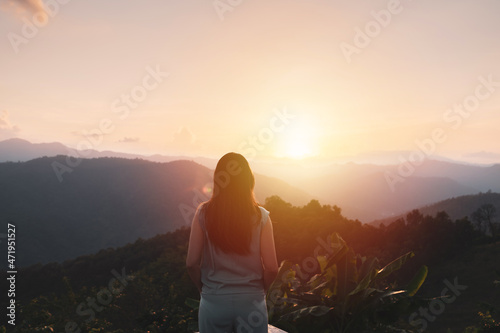 Happy young woman traveler relaxing and looking at the beautiful sunset on the top of mountain © Kittiphan