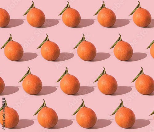 Fruit pattern of fresh tangerine, clementine isolated on pink background with hard shadows. Pop art design, creative summer concept. Citrus in minimal style.