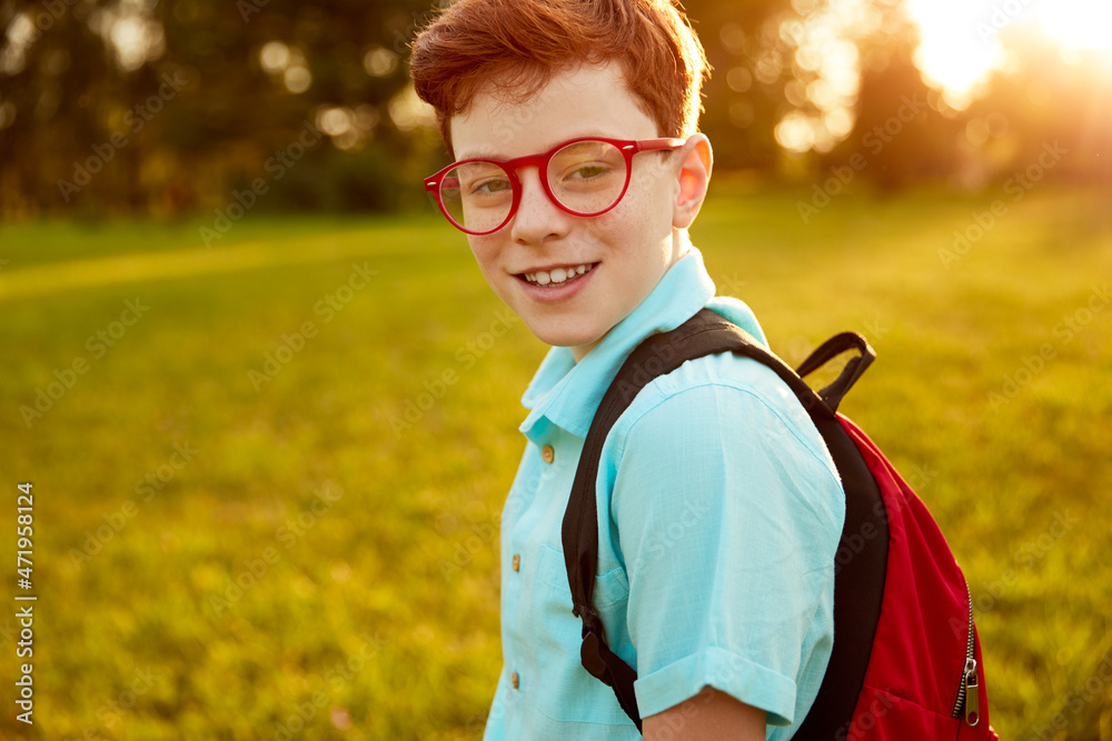 Naklejka premium Clever schoolboy with backpack in park