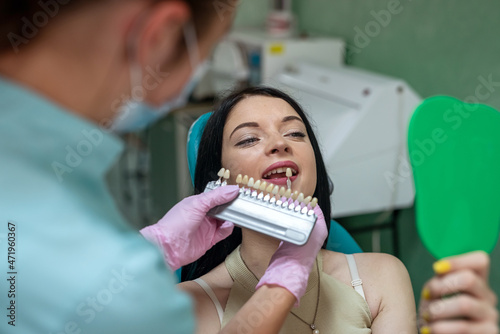 Dentist comparing patient's tooth with color sampler
