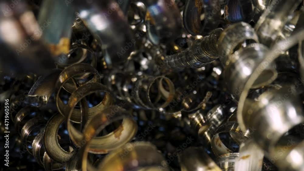 Curly metal chippings after end milling. Macro shot of sharp spirals of silver colored metal. Waste aluminium shavings. Camera pans inside pile of waste metal shavings in slow motion. Close up. Curly metal chippings after end milling. Macro shot of sharp spirals of silver colored metal. Waste aluminium shavings. Camera pans inside pile of waste metal shavings in slow motion. Close up.