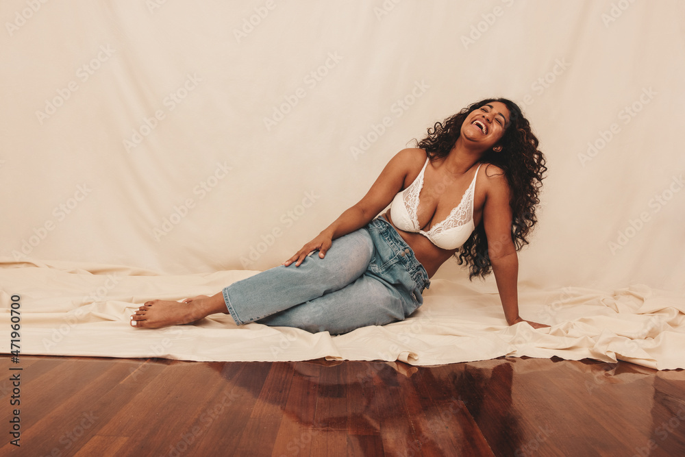 Carefree young woman laughing while sitting on the studio floor Carefree young woman laughing while sitting on the studio floor