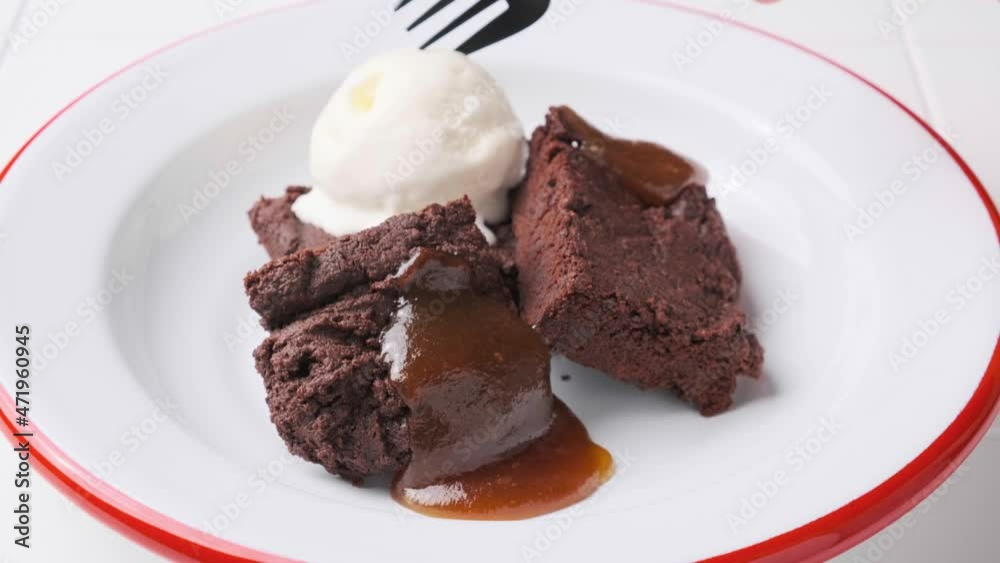 Vegan brownie squares with a scoop of dairy-free ice cream and apple caramel in white plate. Vegan brownie squares with a scoop of dairy-free ice cream and apple caramel in white plate.