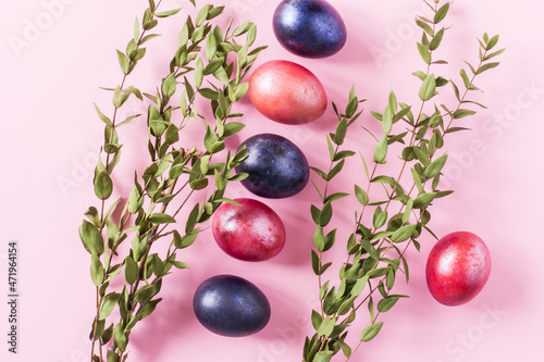 festive Easter composition. green branches multicolored painted eggs on a pink background. view from above.