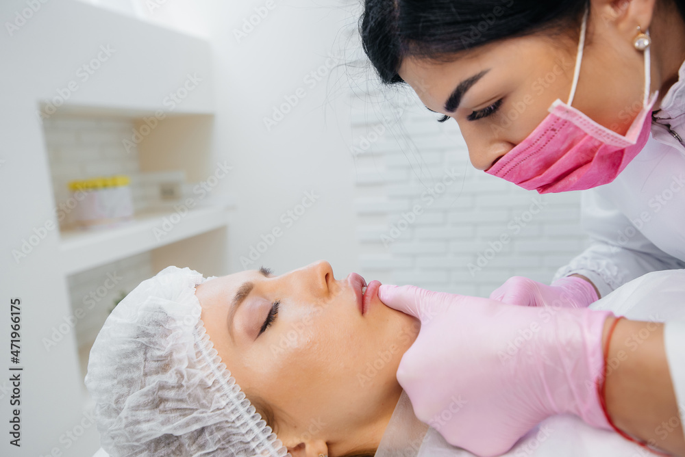 Fototapeta premium Cosmetology procedure for lip augmentation and wrinkle removal for a young beautiful girl. Cosmetology