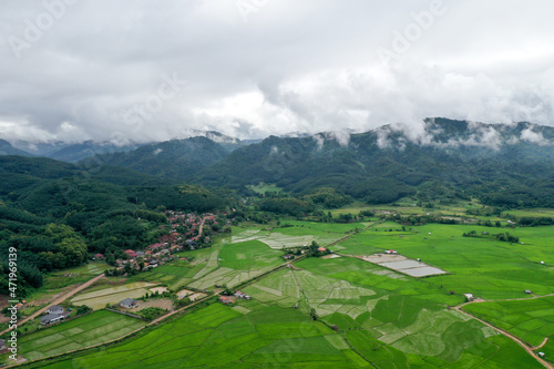 Scenic view of  green field against mountain in cloudy sky