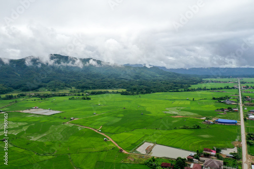 Scenic view of  green field against mountain in cloudy sky