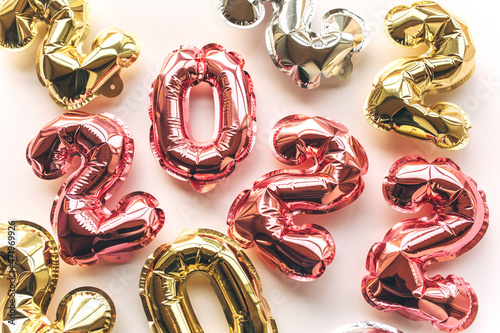 Multicolored Balloons made of foil in the form of numbers 2022 on a pink background . Celebrating Christmas, New Year and festive concept. Flat lay, top view.