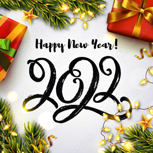 Happy New Year 2022 greeting card. Vector illustration with hand drawn paintbrush lettering 2022, Christmas tree branches, gift boxes, and luminous garlands. Top view.