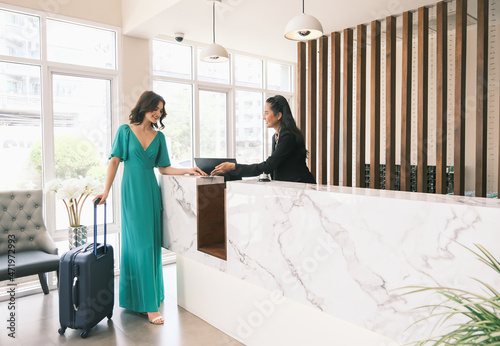 Asia girl receptionist and Caucasian woman traveler checking or checkout in hotel photo