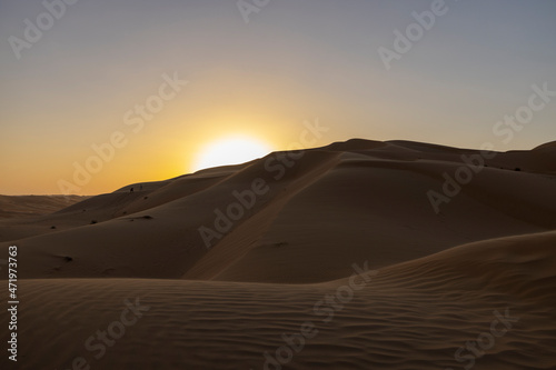 Sunset in the arabian desert with rolling sand dunes in Abu Dhabi, United Arab Emirates