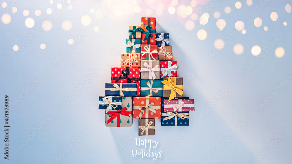 Many gifts in sunlight laid out on blue background in the shape of a Christmas tree