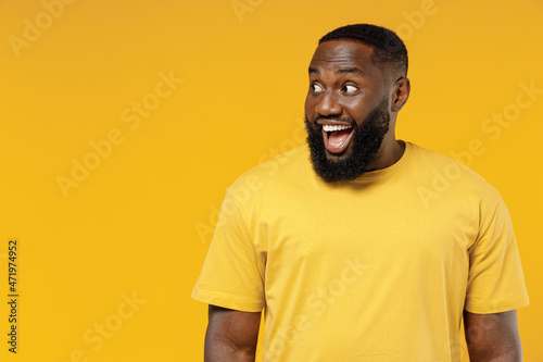 Canvas Print Young smiling happy fun black man 20s wearing bright casual t-shirt look aside on copy space workspace area mock up isolated on plain yellow color background studio portrait