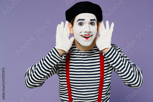 Fun young mime man with white face mask wears striped shirt beret holding hands near ears try to hear you overhear listening intently isolated on plain pastel light violet background studio portrait. photo