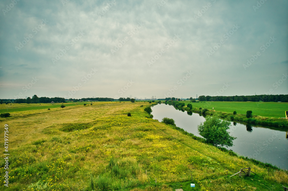 Drone view of the Vecht river, green grass, blue water, city with high voltage poles. Vechtdal, Dalfsen the Netherlands Drone view of the Vecht river, green grass, blue water, city with high voltage poles. Vechtdal, Dalfsen the Netherlands