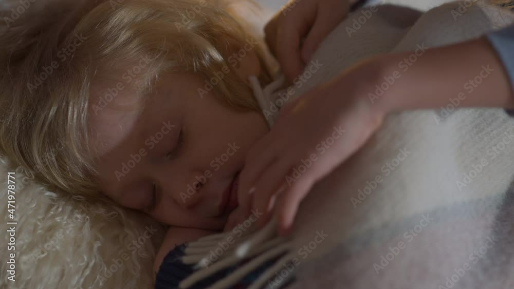 Close-up happy charming brother sleeping as sister covering sibling with blanket kissing cheek. Caucasian boy resting at home indoors with loving girl taking care of child Close-up happy charming brother sleeping as sister covering sibling with blanket kissing cheek. Caucasian boy resting at home indoors with loving girl taking care of child