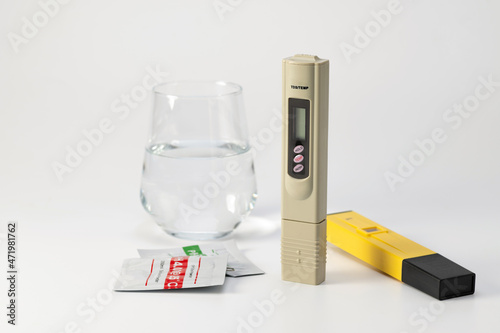 A set of meters pH meter and TDS for water quality control. Salt meter and pH meter in a glass of water on a white background. Water hardness, salt meter. Drinking water quality analyzer.