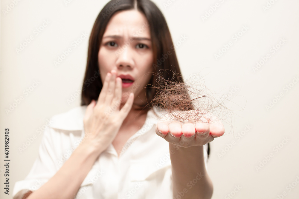 Asian women looking hair loss falling in hand with a worry Asian women looking hair loss falling in hand with a worry