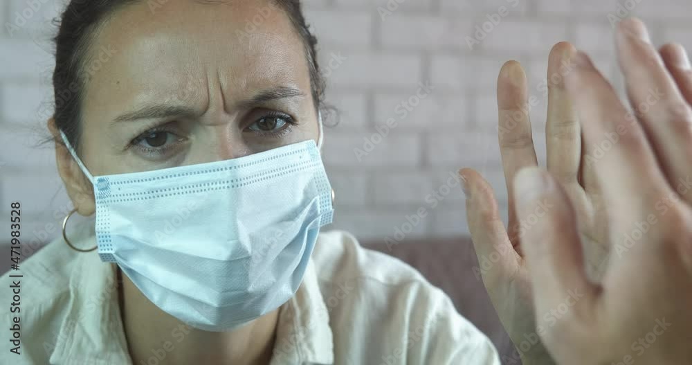 Self isolation by window. A quarantined woman in protective mask touch the window on man hand in the room. Self isolation by window. A quarantined woman in protective mask touch the window on man hand in the room.