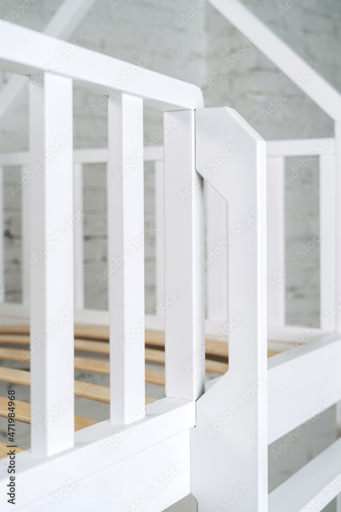 Fototapeta premium The image of the grates child's bed against the backdrop of the white wall.