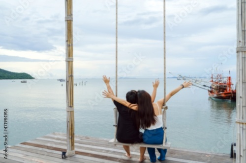 blurred of back view of two asian women having fun together on seaside