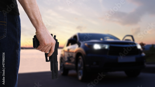 Man with gun near luxury car outdoors, closeup © New Africa